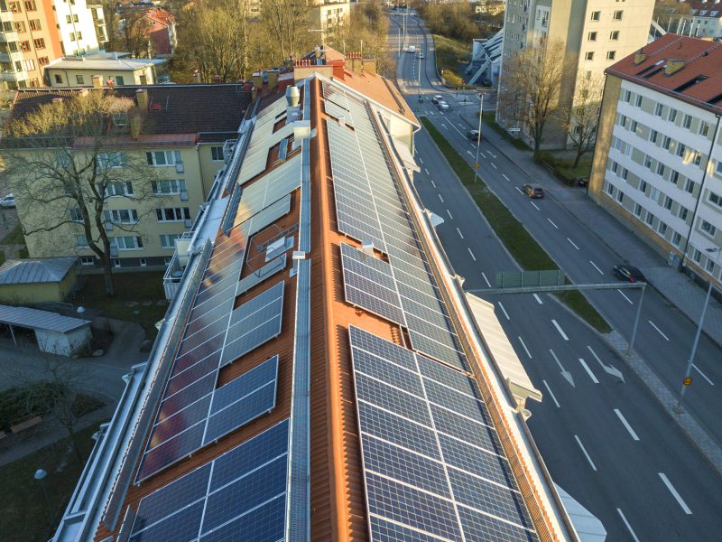 Aerial view of solar photo voltaic panels system on apartment building roof. Renewable ecological green energy production concept.
