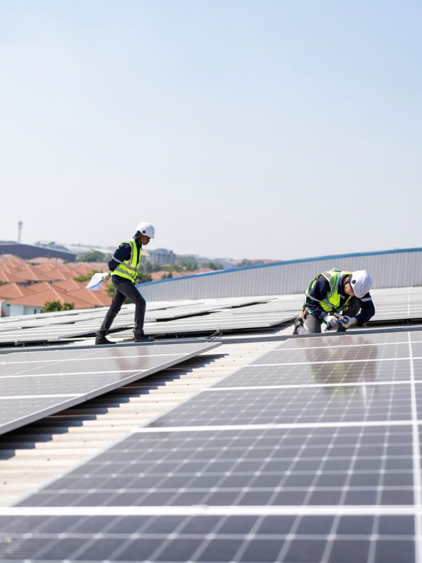 Engineer on rooftop kneeling next to solar panels photo voltaic with tool in hand for installation
