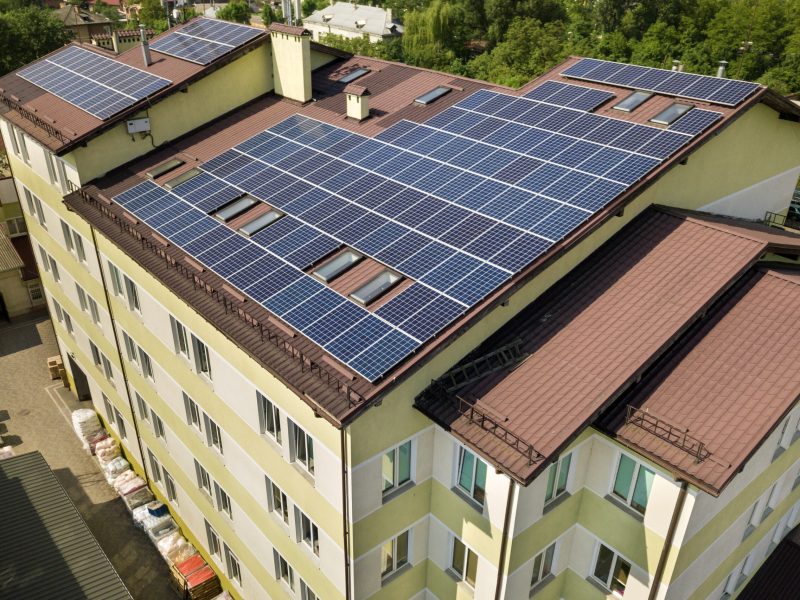 Aerial view of many solar panels mounted of industrial building roof.