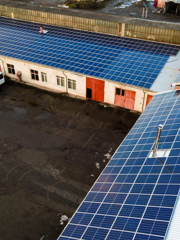 Aerial view of surface of blue photovoltaic solar panels mounted on industrial  building roof for producing clean ecological electricity. Production of renewable energy concept.