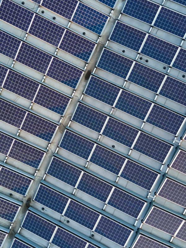 Aerial view of solar power plant with blue photovoltaic panels mounted on industrial building roof for producing green ecological electricity. Production of sustainable energy concept.